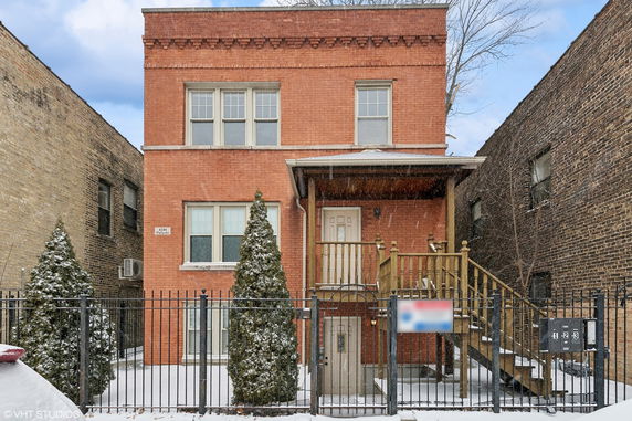 Front view of a brick two-story building with a wooden staircase and railing.