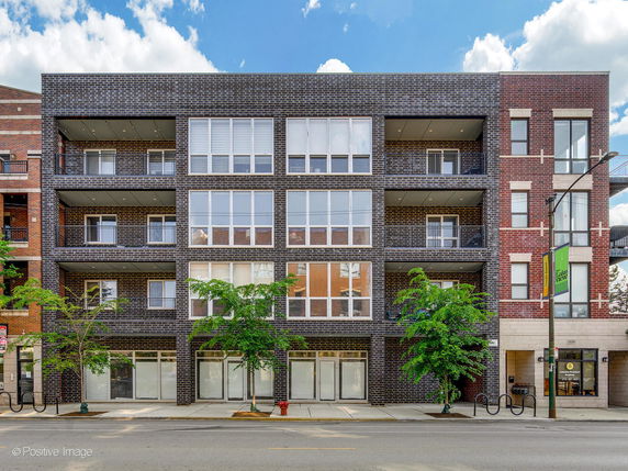 Front view of a multi-story brick building with large windows and balconies.