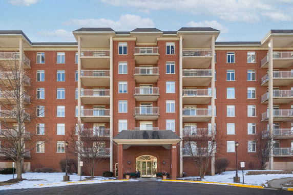 Front view of a multi-story brick apartment building with balconies.