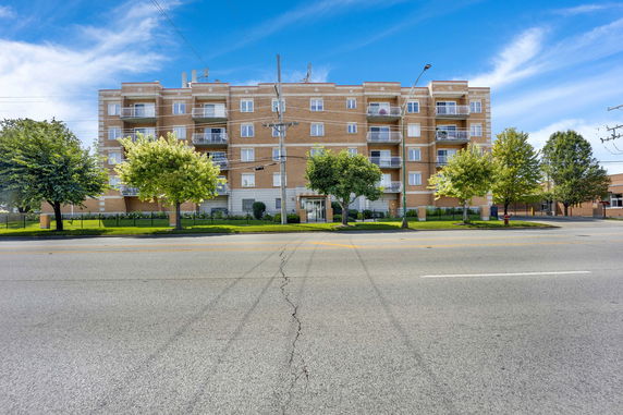 Front view of a multi-story apartment building with balconies.