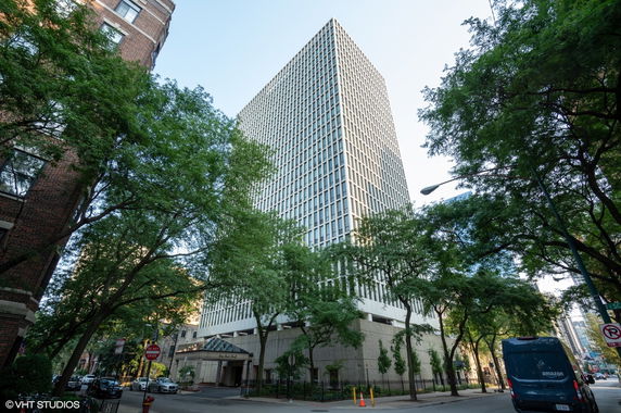 Front view of a tall high-rise building surrounded by trees.