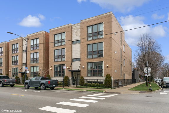 Front view of a multi-story building with large windows and a brick facade.