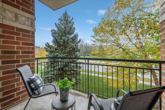 View from a balcony with seating overlooking trees and a street.