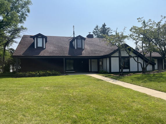 Front view of a two-story house with dormer windows and dark roof.