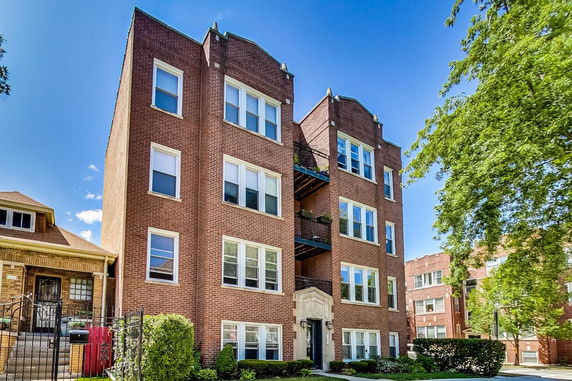Front view of a multi-story brick apartment building with multiple windows and balconies.