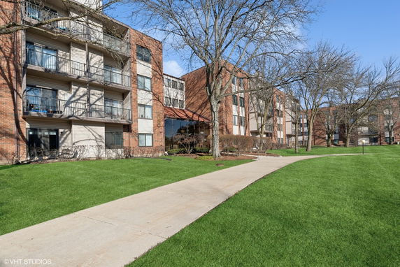 Front view of a multi-story apartment building with balconies and brick facade.
