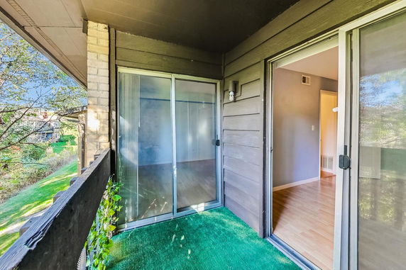 View from a building balcony with sliding glass doors and green flooring.