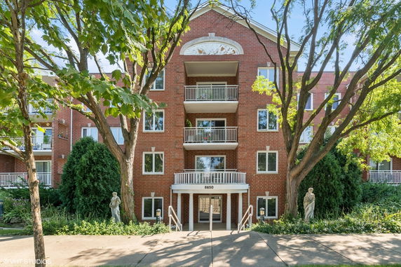 Front view of a multi-story brick apartment building with balconies.