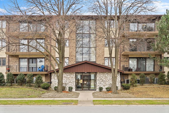 Front view of a multi-story building with balconies and a central entrance.
