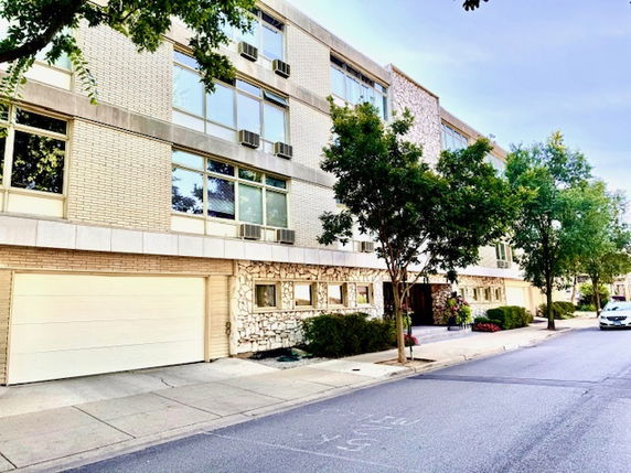 Front view of a multi-story residential building with large windows and a garage.