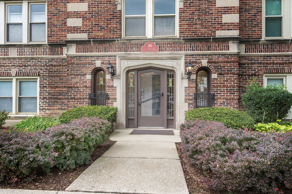 Front view of a brick building with decorative doorway and exterior lighting.