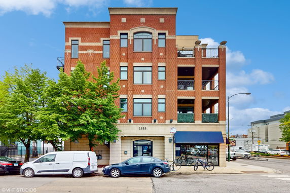 Front view of a multi-story brick building with large windows and balconies.