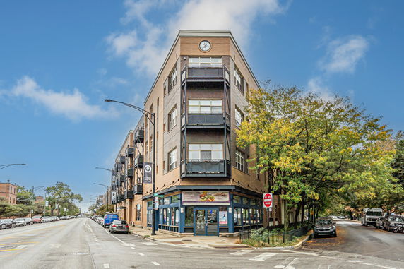Front view of a multi-story brick building on a street corner.