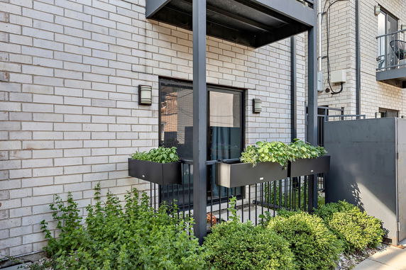 Front view of a building with a balcony featuring a planter and boxed windows.