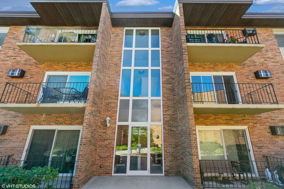 Front view of a brick apartment building with balconies.