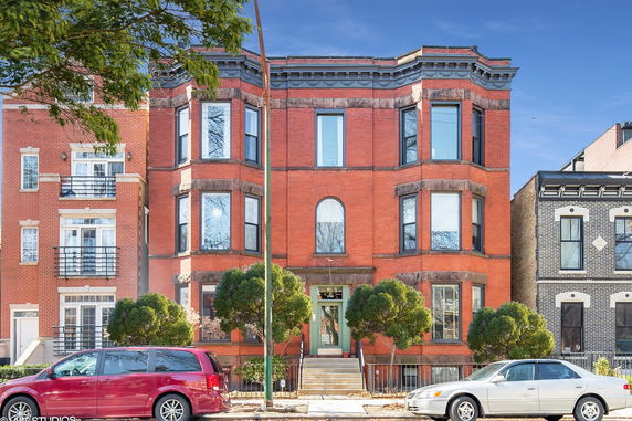 Front view of a multi-story brick building with large windows and an entrance with steps.