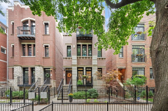Front view of a brick multi-story residential building with balconies.