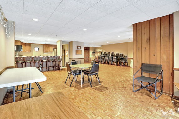 Interior view of a recreation area with tables, chairs, and a bar counter.