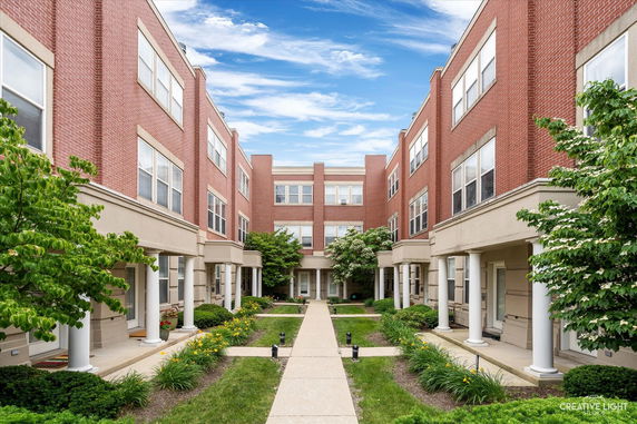 Front view of a three-story brick apartment building with a courtyard.