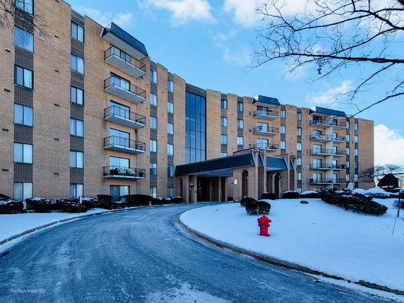 Front view of a multi-story apartment building with balconies and a central entrance.