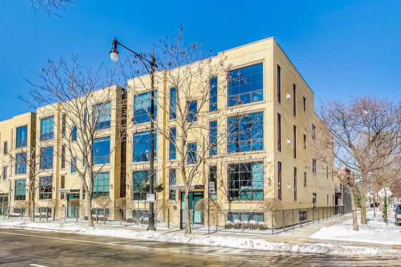 Front view of a multi-story brick building with large windows.