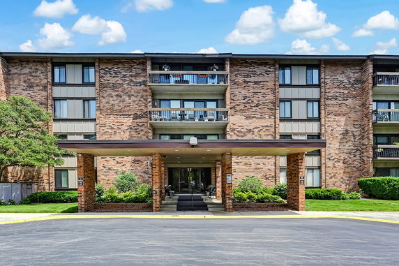 Front view of a multi-story brick apartment building with a covered entrance.