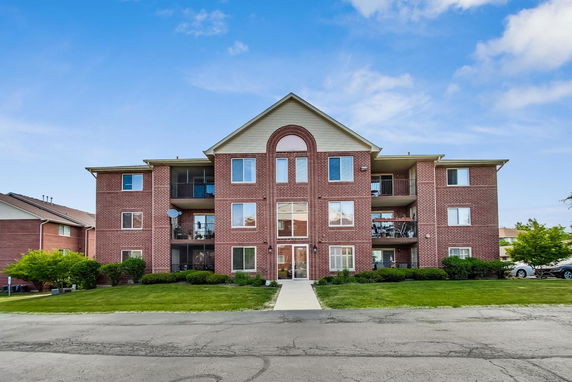 Front view of a brick apartment building with multiple balconies.