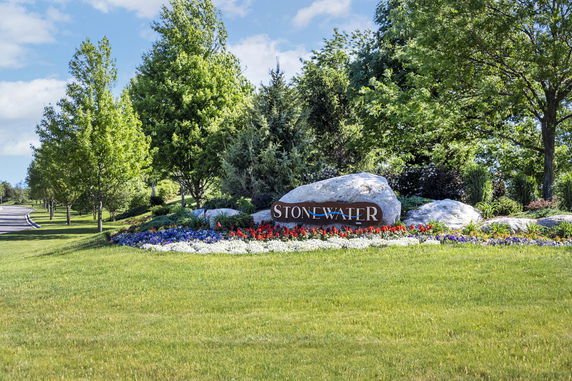 Landscaped area with a sign that reads 'STONEWATER' surrounded by rocks and flowers.