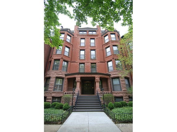 Front view of a multi-story brick apartment building with an entrance staircase.