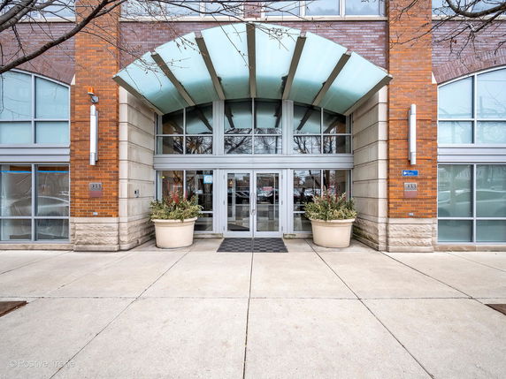 Front view of a building entrance with glass doors and decorative planters.