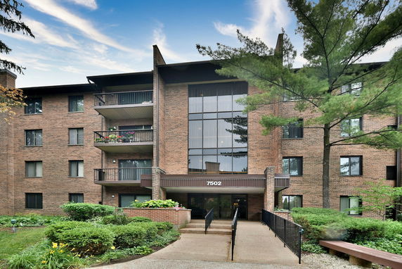 Front view of a multi-story brick building with balconies and large windows.