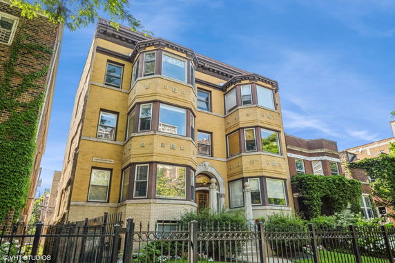 Front view of a multi-story building with large bay windows and brick facade.