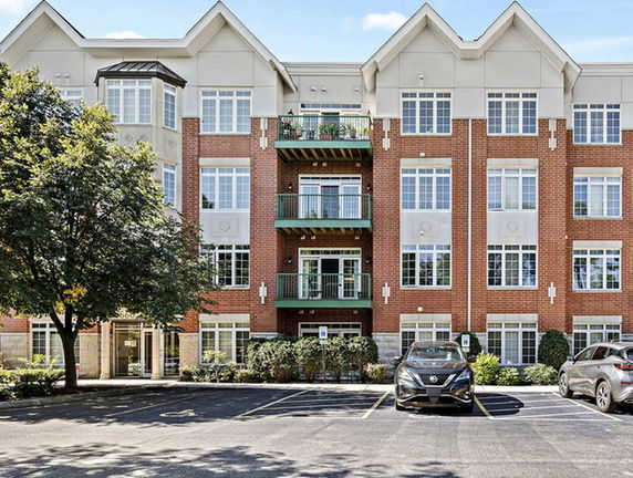 Front view of a multi-story residential building with a brick facade and balconies.