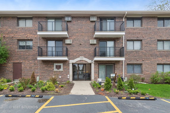 Front view of a brick apartment building with balconies and a central entrance.
