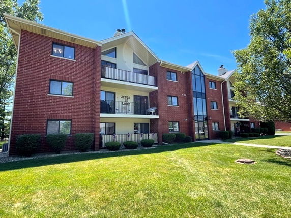 Front view of a multi-story brick apartment building with balconies.