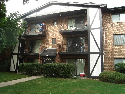 Front view of a multi-story brick apartment building with balconies.