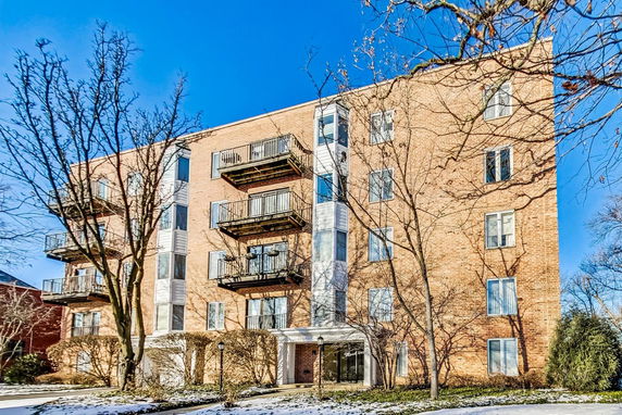 Front view of a multi-story brick apartment building with balconies.