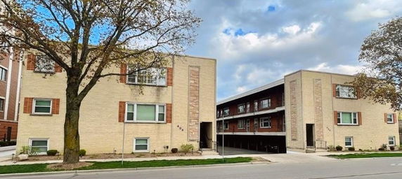 Front view of a multi-story apartment building with open parking area underneath.
