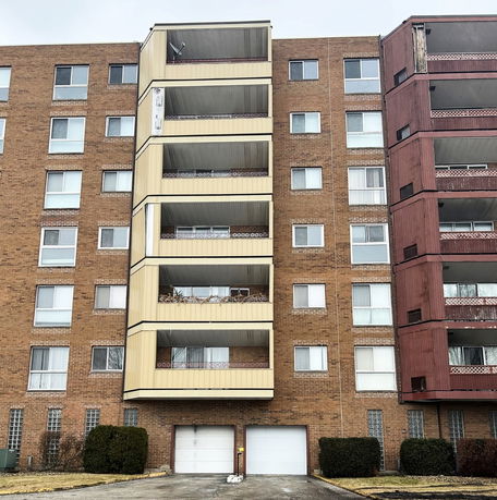 Front view of a multi-story brick building with balconies and garages.