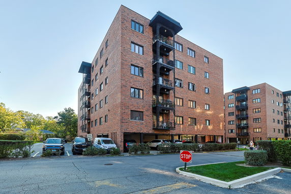 Front view of a multi-story brick apartment building with balconies.