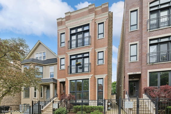 Front view of a four-story brick townhouse with balconies.