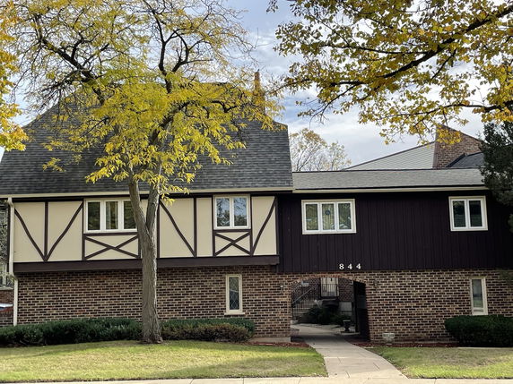 Front view of a two-story house with a brick lower half and timber detailing on the upper half.