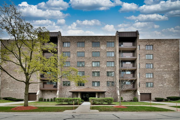 Front view of a multi-story brick apartment building with balconies.