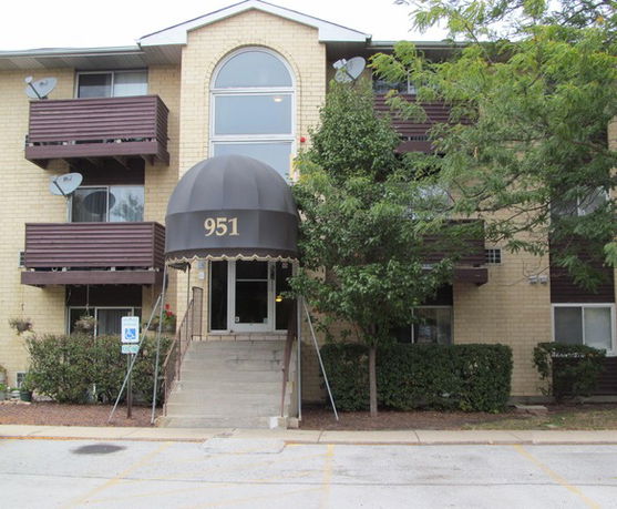 Front view of a multi-story apartment building with a central entrance marked by a canopy.