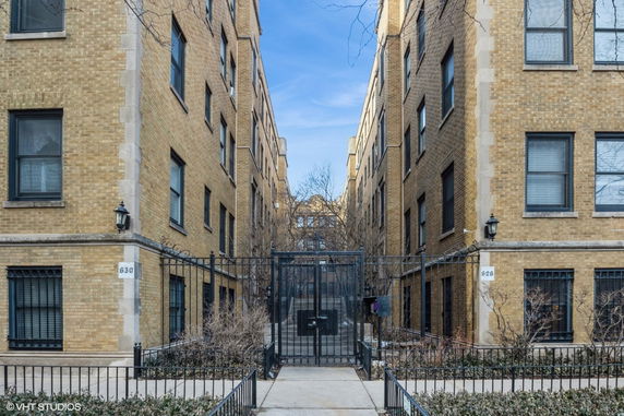 Front view of a multi-story brick apartment building with iron gate.