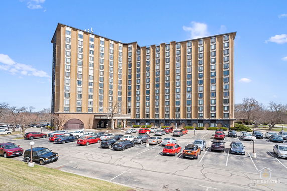 Front view of a multi-story apartment building with a parking area in front.