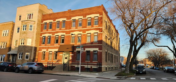 Front view of a multi-story brick building on a street corner.