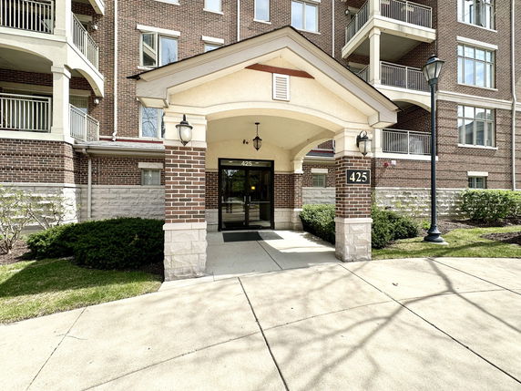 Front entrance of a multi-story brick apartment building with balconies.