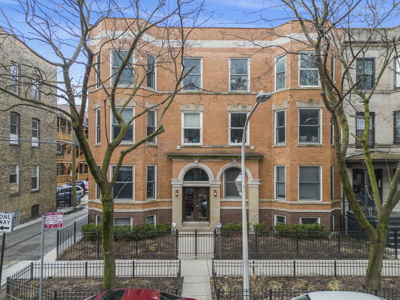 Front view of a multi-story brick building with arched entrance.