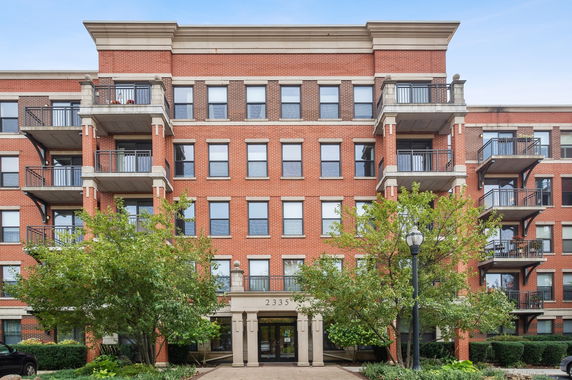Front view of a multi-story brick building with balconies and entryway.